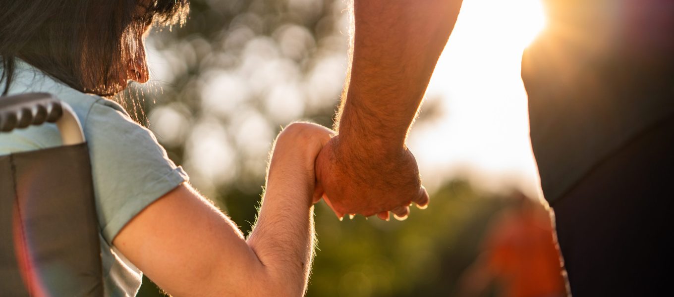 Close up women on a wheel chair holding mens hand