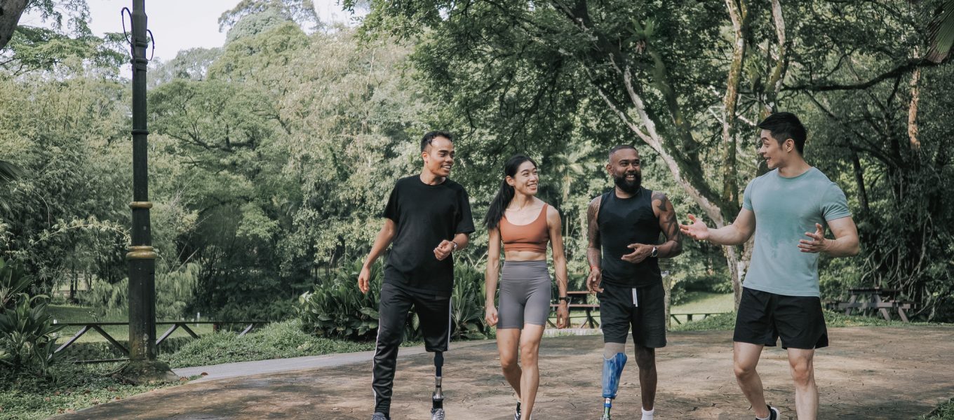 Asian mid adult athlete with disability and friends jogging in public park Asian mid adult athlete with disability and friends jogging in public park