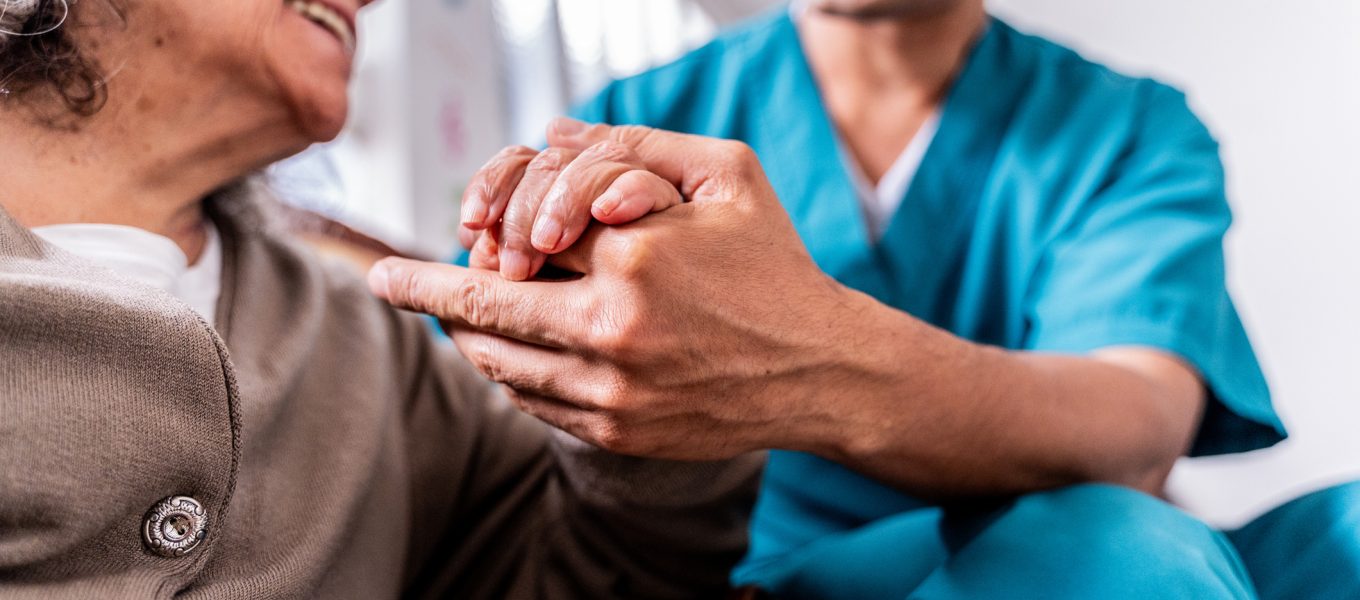 Senior woman holding caregiver’s hands at home Senior woman holding caregiver's hands at home